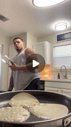 a man standing in front of a frying pan with food on top of it