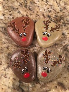 three heart shaped rocks with reindeer faces painted on them, sitting on a marble counter top