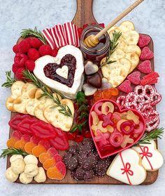 a platter filled with heart shaped cookies, crackers and other food on top of a table