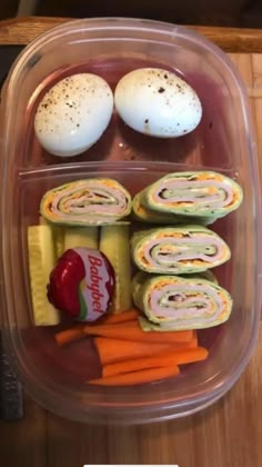 a plastic container filled with food on top of a wooden table next to an egg