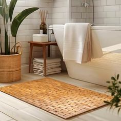 a bath room with a toilet and a plant next to it on the floor in front of a tub