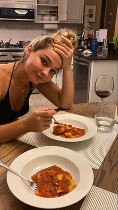 a woman sitting at a table with two plates of food