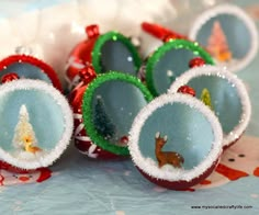 small christmas ornaments are sitting on a table with snow and trees in the holes inside them