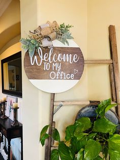 a welcome sign hanging on the wall next to a ladder with potted plants in it