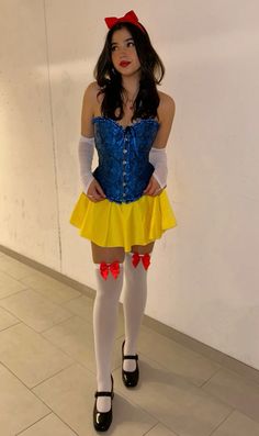 a woman dressed as snow white standing in front of a wall with her hands on her hips