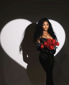 a woman standing in front of a heart shaped shadow with flowers on her chest and long black dress