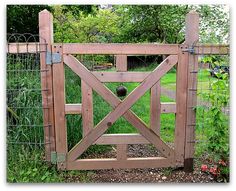 a wooden gate in the middle of a grassy area