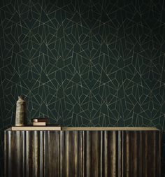 the wallpaper is very dark green and has gold lines on it, as well as a vase