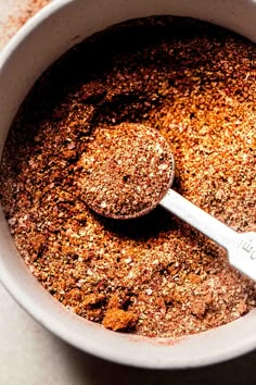 a white bowl filled with ground spices and a wooden spoon in the bottom right corner