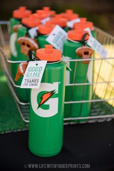 several green jugs with orange lids are on display in a metal basket at an outdoor event