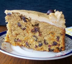 a piece of cake with white frosting and raisins sits on a plate