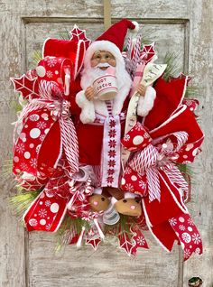 a christmas wreath with santa claus holding a mug and candy canes in it's mouth