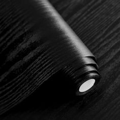 a roll of black paper sitting on top of a wooden table next to a light