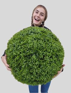 a woman holding a large round bush in front of her face and smiling at the camera