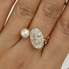 a woman's hand with a ring on it and a pearl in the middle