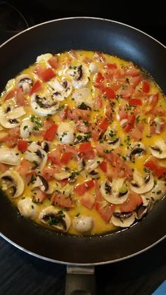 an omelet with mushrooms and tomatoes in a pan