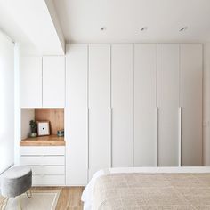 a bedroom with white cupboards and a bed