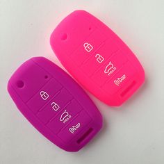 two pink and purple car keys sitting next to each other on top of a white surface