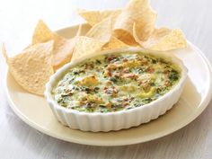 a white plate topped with a bowl of dip and tortilla chips