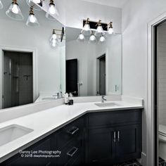 a bathroom with black and white tile flooring and vanity lights above the sink area