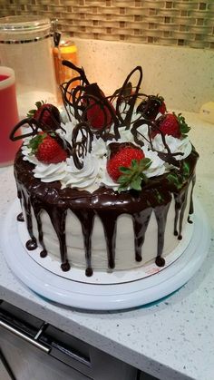 a chocolate covered cake with strawberries on top and drizzled in chocolate