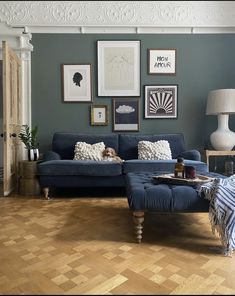 a living room with blue couches and pictures on the wall above them in various frames