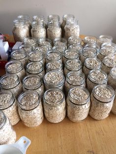 many jars filled with oatmeal sitting on top of a wooden table