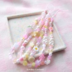 three bracelets are sitting on top of a white tray with pink and yellow beads