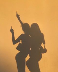 the shadow of two people holding umbrellas in front of an orange sky with white clouds