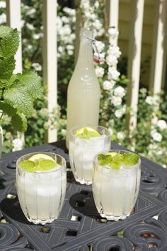 three glasses filled with ice and limes sitting on a table next to a bottle