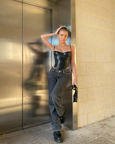 a woman leaning against a wall with her hand on her head and wearing black boots