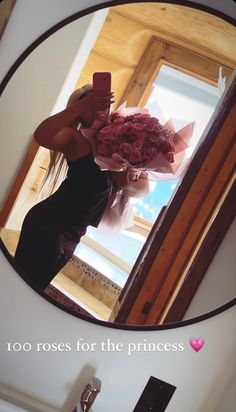 a woman taking a selfie in front of a mirror holding a bouquet of flowers