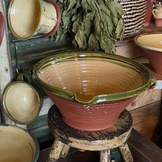 a large bowl sitting on top of a wooden table next to other bowls and containers