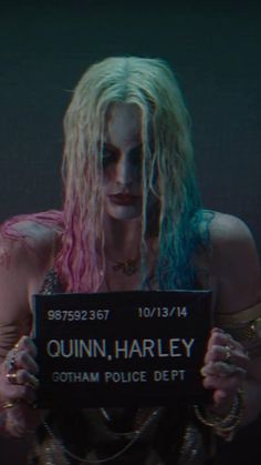 a woman with blonde hair and makeup holding a sign that reads,'queen harley gotham police dept '