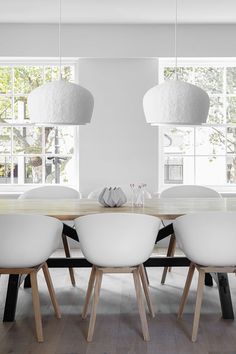 a dining room table with white chairs and a chandelier