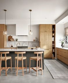 an image of a kitchen setting with bar stools and island in the middle,