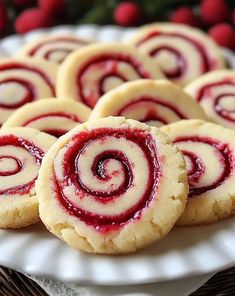 some cookies are on a white plate with raspberry sauce in the middle and one is cut into spirals