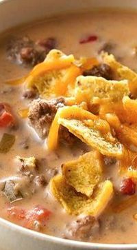 a close up of a bowl of soup with meat and potato chips on the side