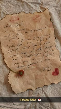 an old piece of paper with writing on it and a flower sticking out of it