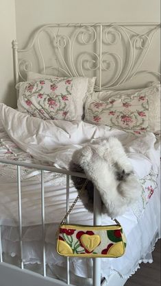 a white bed topped with pillows and a purse