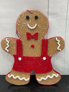 a ginger with a bow tie and red overalls is standing on a table in front of a white wall