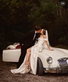 a bride and groom sitting on top of a white car