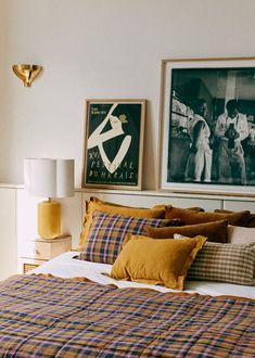 a bed with plaid comforter and pillows in a bedroom next to pictures on the wall