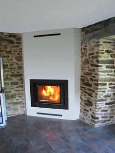 a room with a fire place in the center and stone walls on both sides,