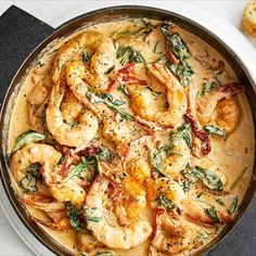 a pan filled with shrimp and spinach covered in sauce