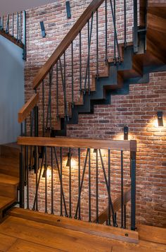 a brick wall and wooden stairs with lights on them in a room that has wood flooring