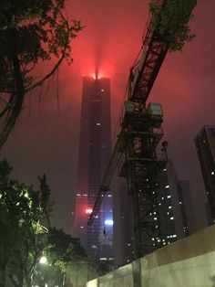 the skyscrapers are lit up at night with red lights in the sky above them