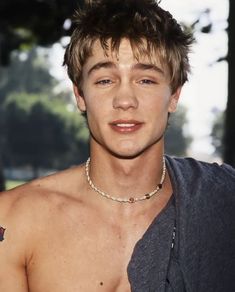 a shirtless young man wearing a chain around his neck