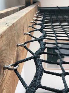 a close up view of a metal net on the side of a wooden beam with a window in the background