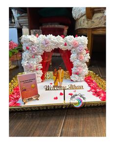 a decorated welcome sign with flowers and decorations on the front, sitting on a wooden floor